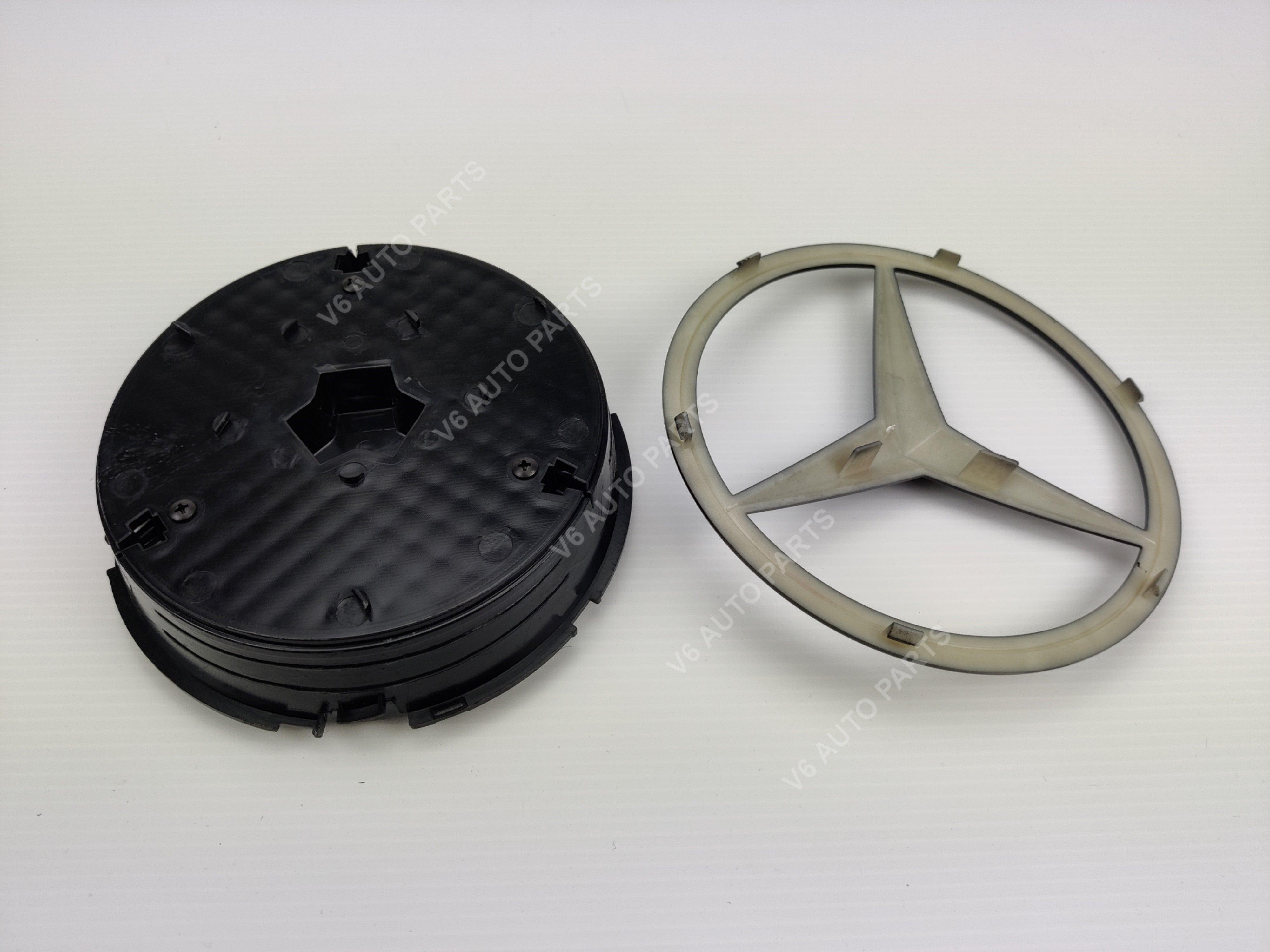 Front Grille Black Centre Emblem Badge For A B C CLA E with black plastic wheel and Mercedes logo.
