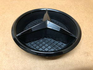 A sleek black Mercedes emblem badge for 2016+ Benz E-Class W213 front grille displayed on a table.